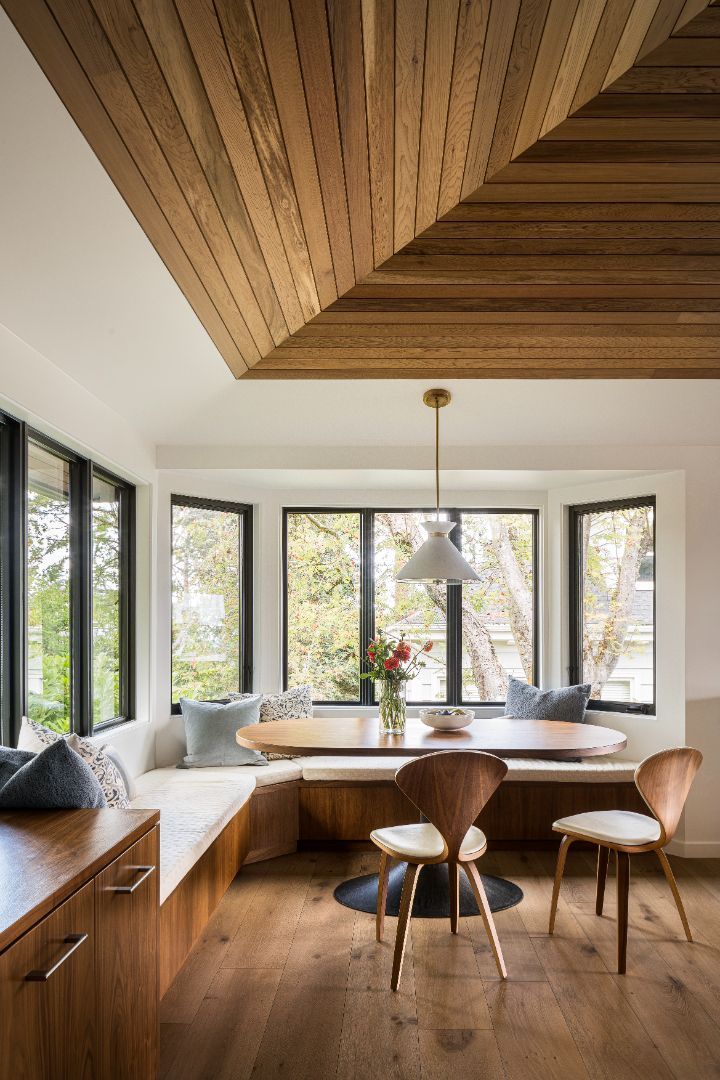 A dining room with a table and chairs and a wooden ceiling.