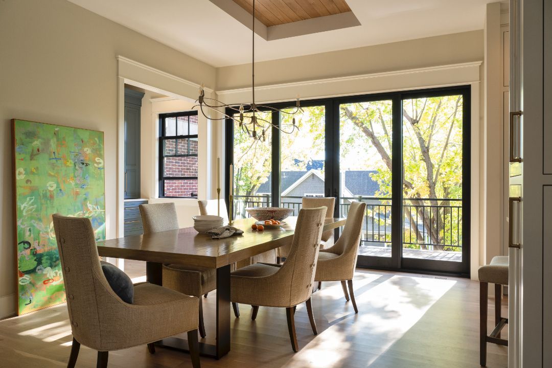 A dining room with a table and chairs and a lot of windows.