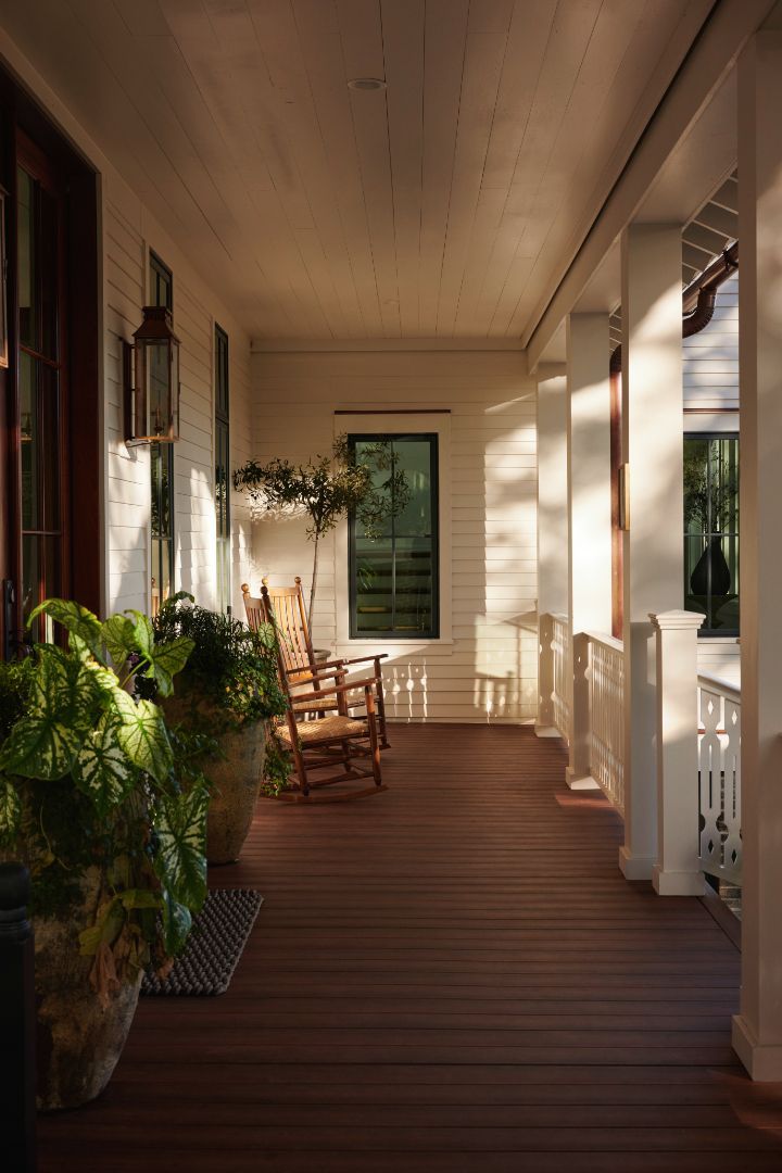 There are two rocking chairs on the porch of a house.