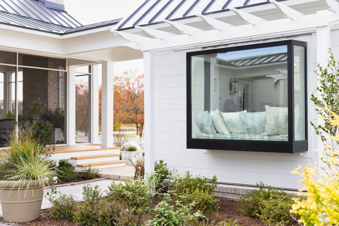 A white house with a large window on the side of it.