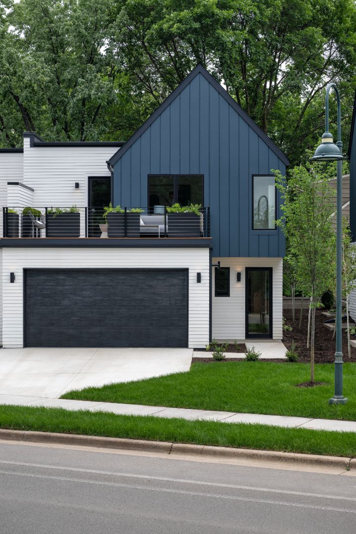 A blue and white house with a garage and a balcony.