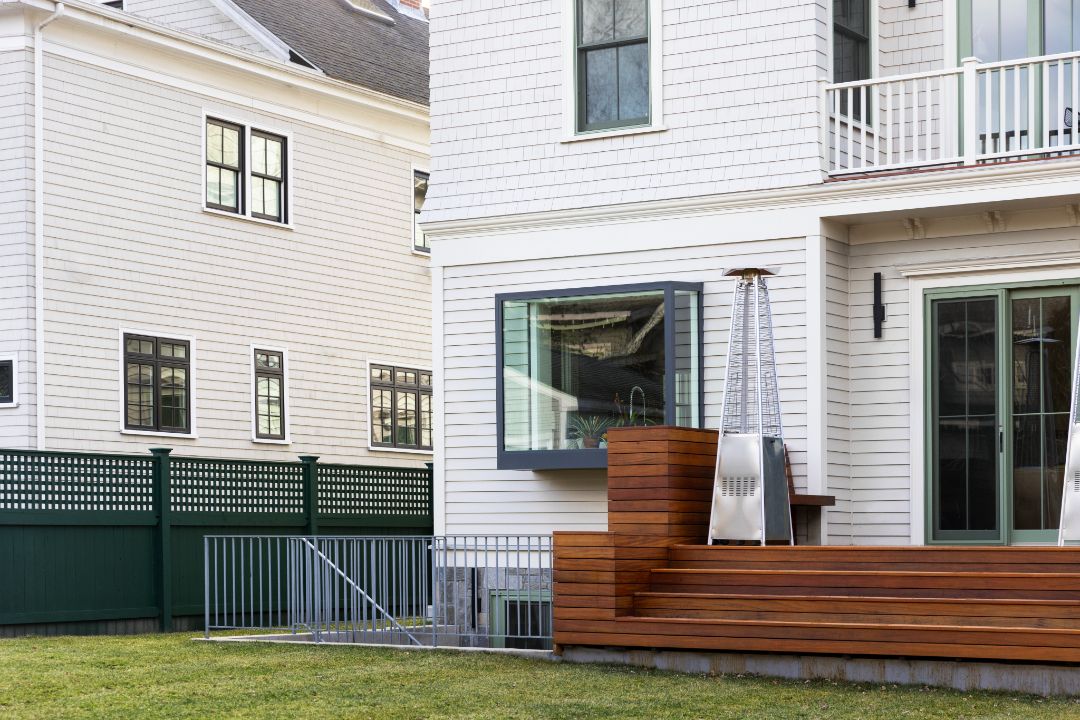 A white house with a wooden deck in front of it.