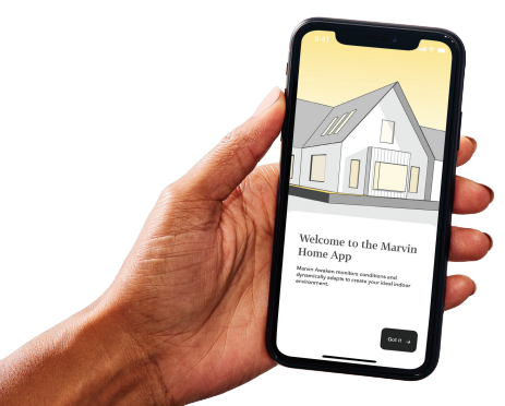 A person is holding a cell phone with a house on the screen.