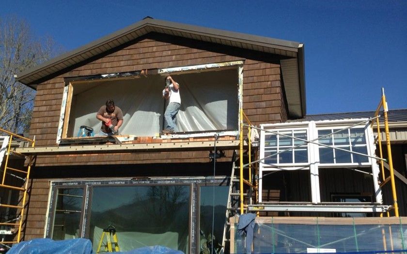 Two men are working on the side of a house.