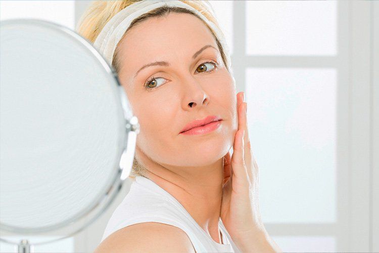 woman staring in the mirror after botox