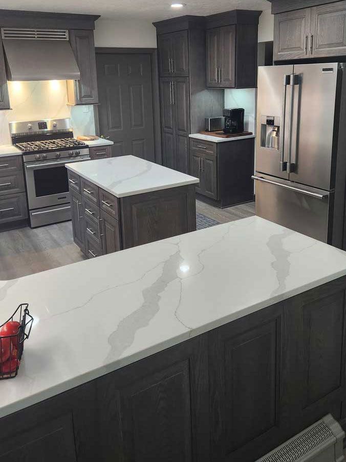 A kitchen with stainless steel appliances and a large island in the middle.