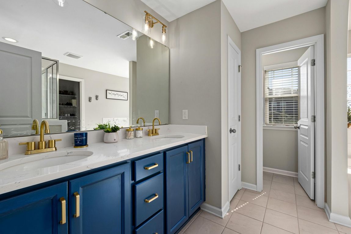 A bathroom with two sinks , a mirror , and blue cabinets.