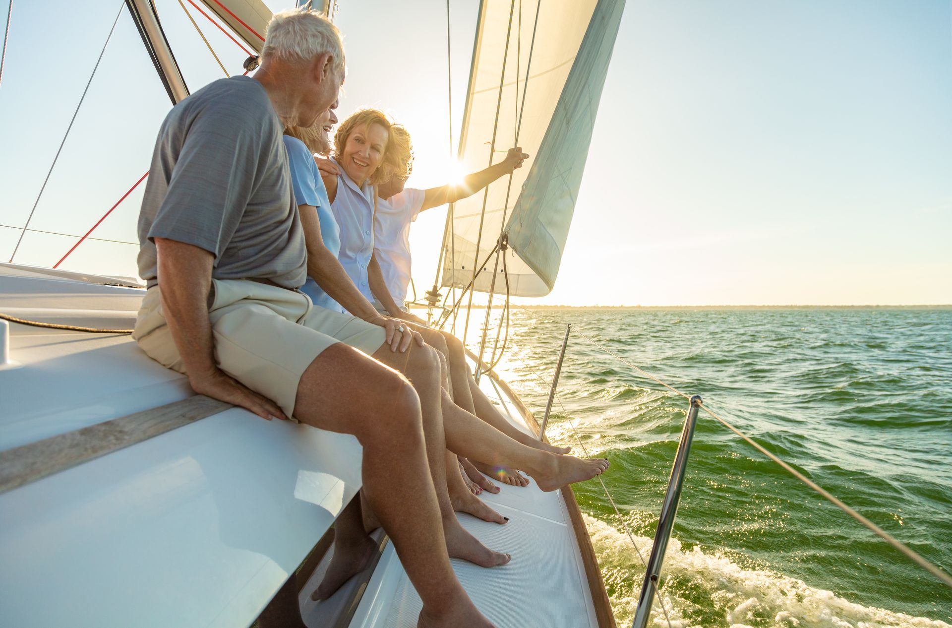 Group of people on a sailboat, enjoying the sunny sea. One person points to the distance.