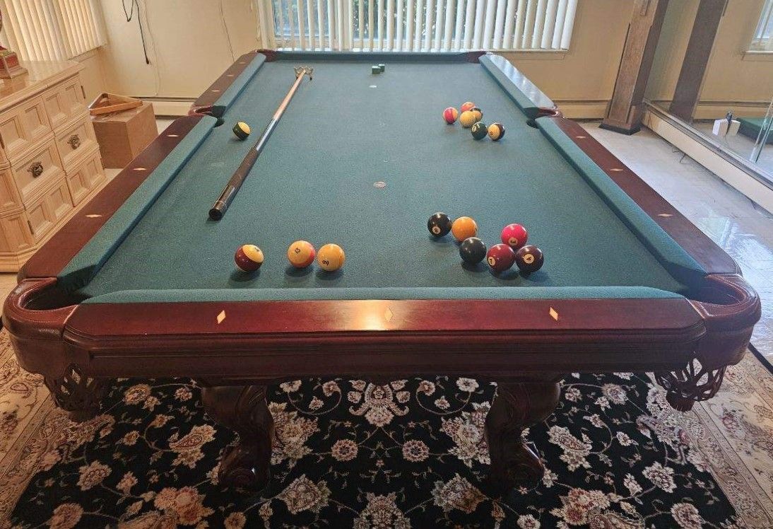 A pool table with balls and a cue on it