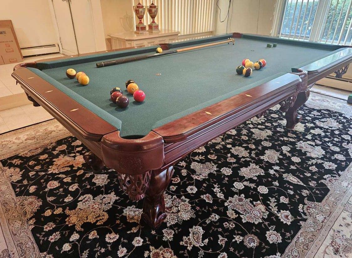 A pool table is sitting on top of a rug in a living room.