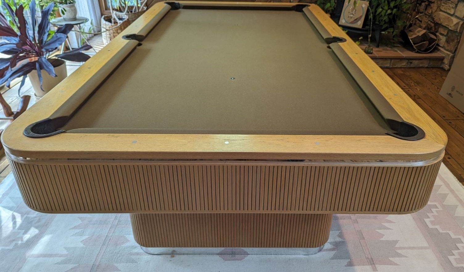 A pool table with a ball on it in a room with stairs