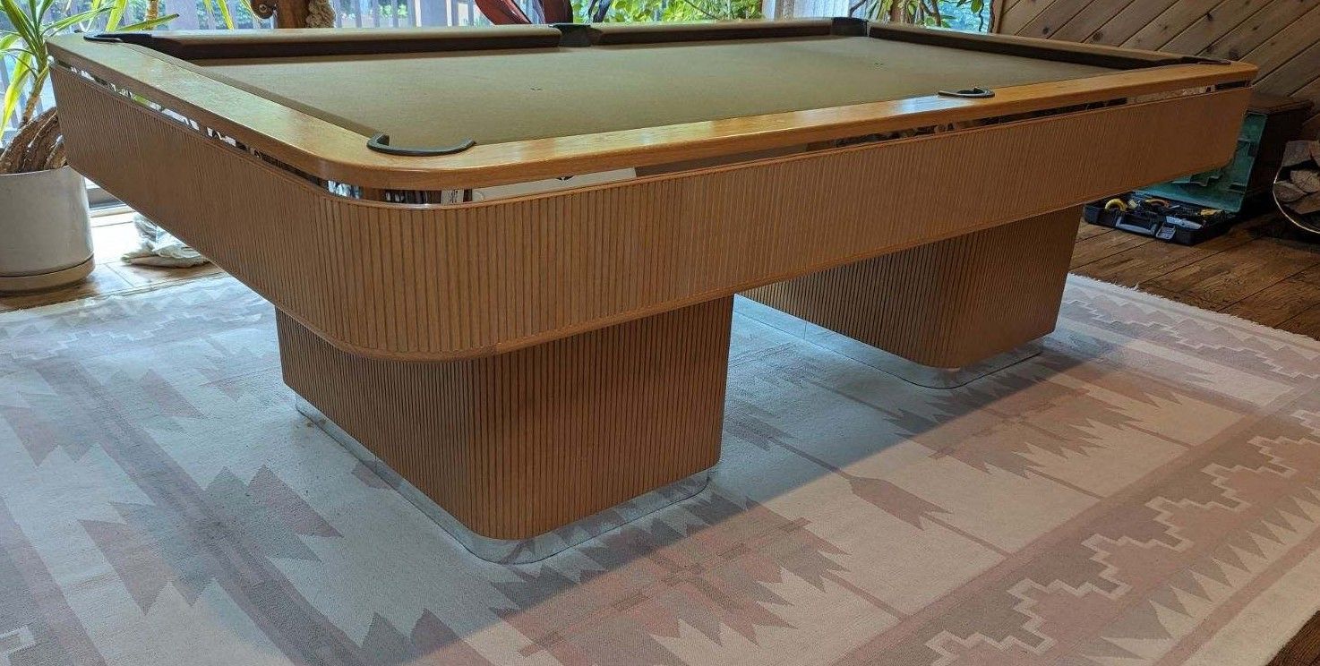 A pool table with balls on it is sitting on a wooden floor