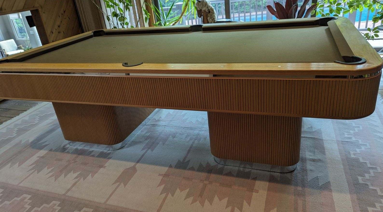 A pool table in a room with stairs in the background