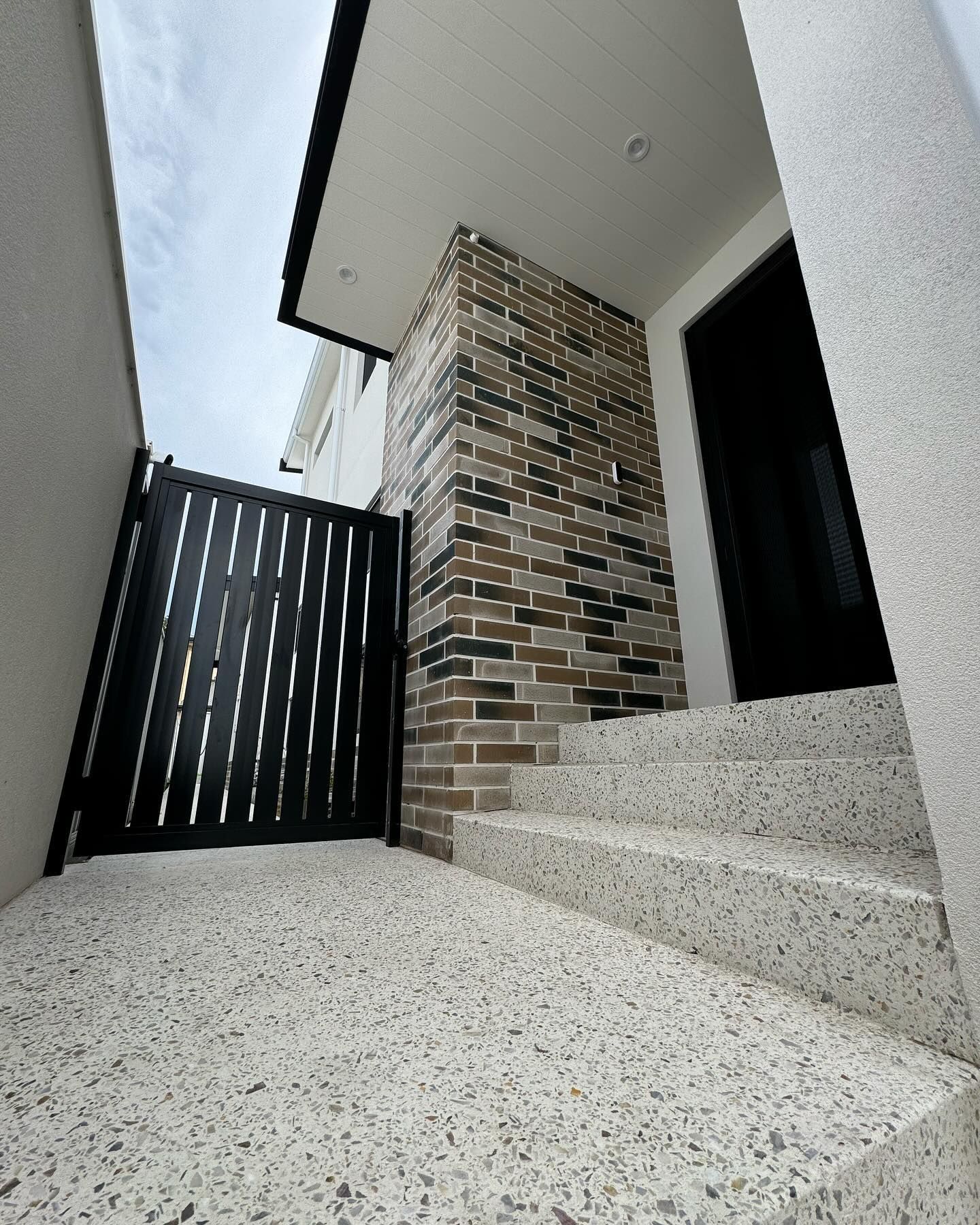 Honed concrete stair case leading into two storey home with side access gate 