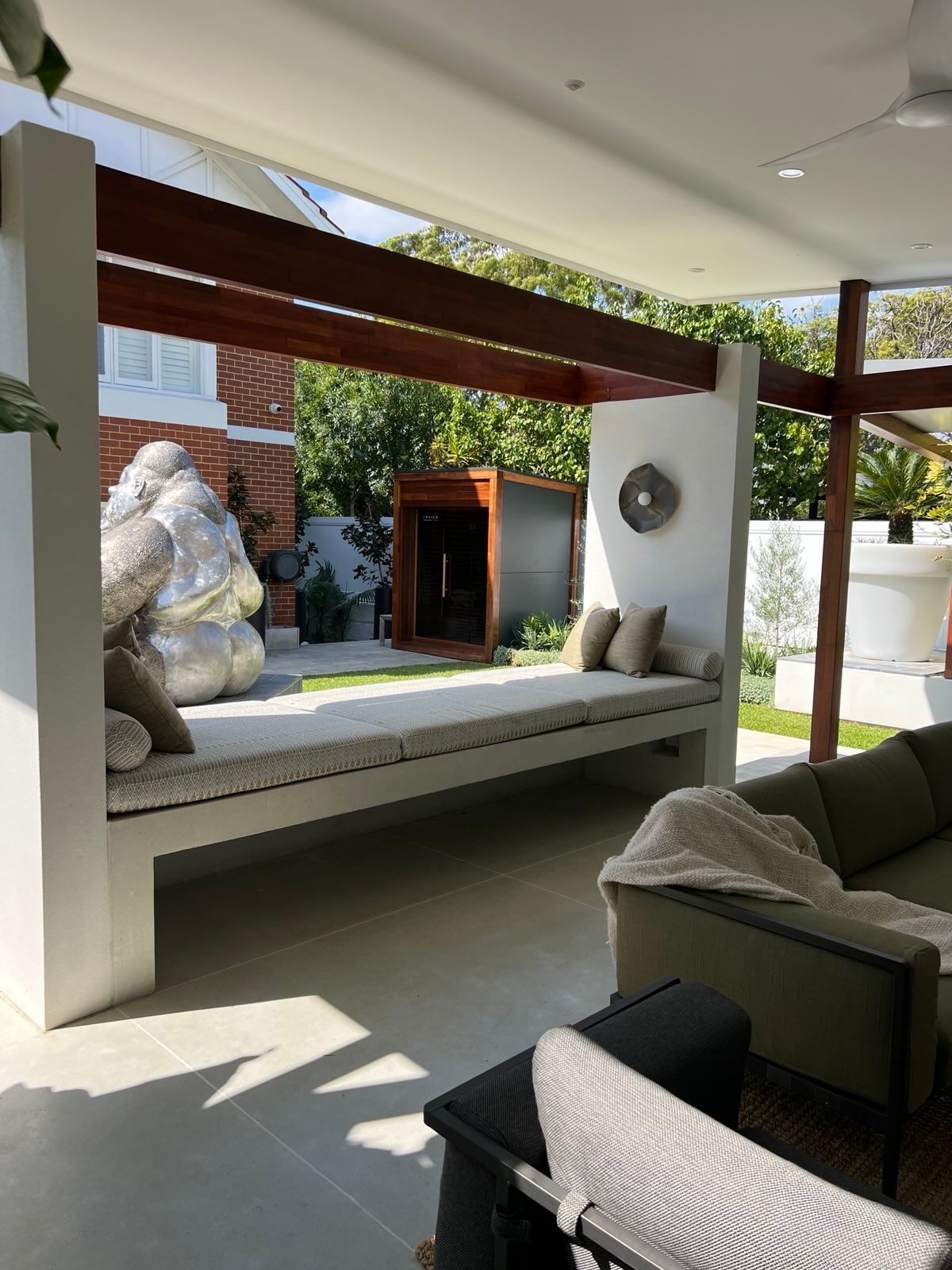 Outdoor seating area with a built-in bench, pillows, and a sculpture.