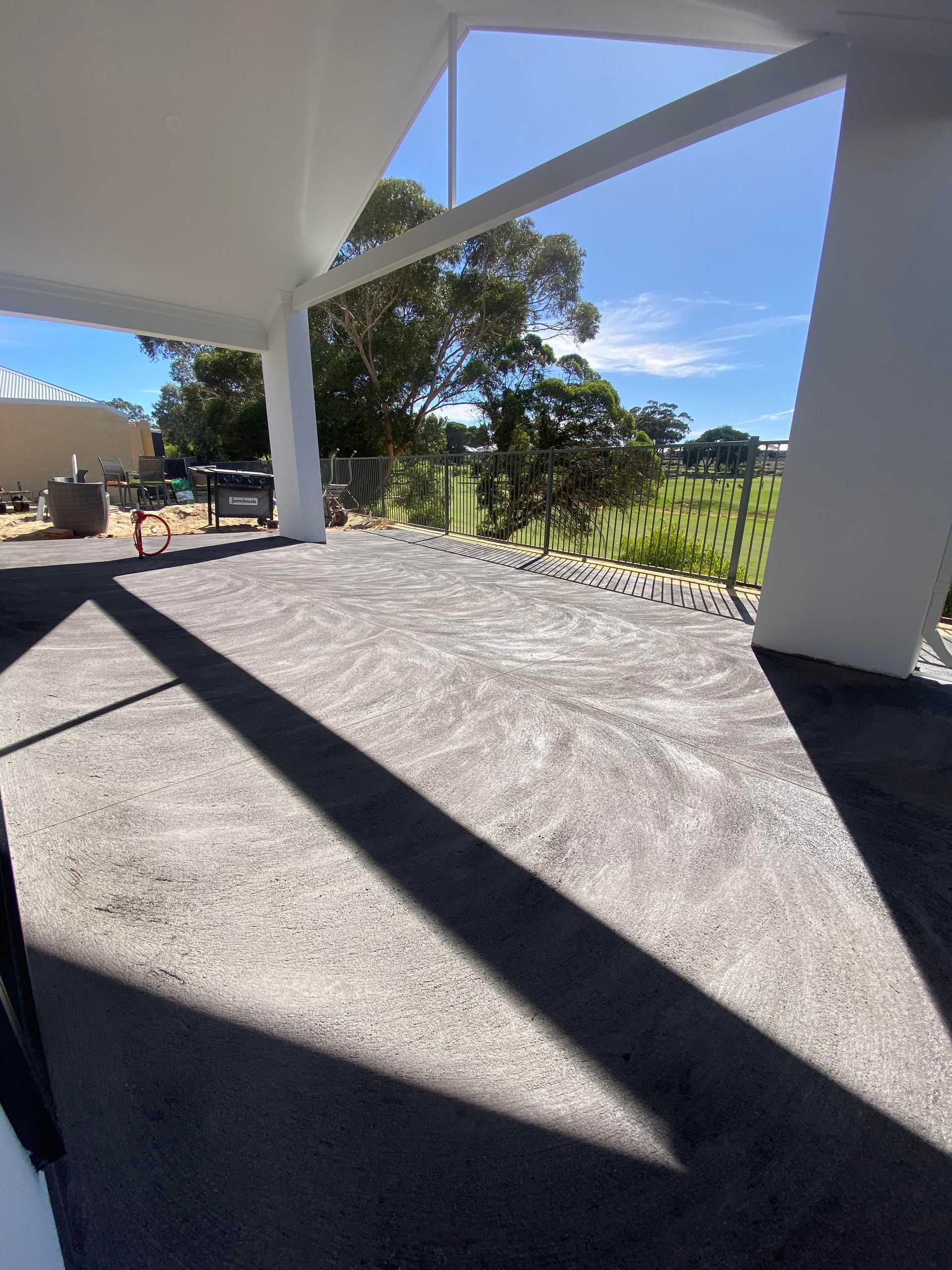 A charcoal concrete patio flooring in backyard oh Perth home backing in the golf course.