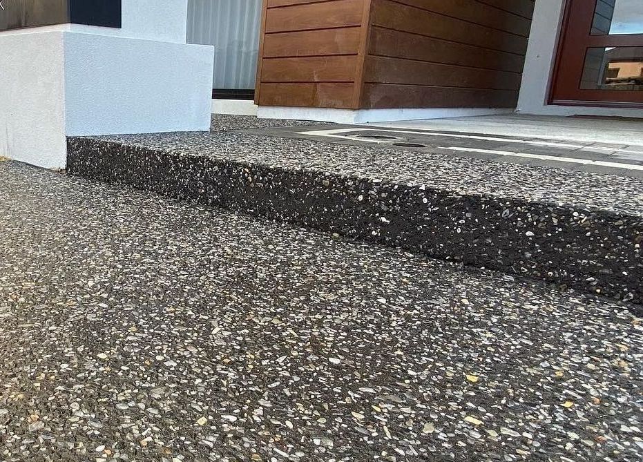Charcoal exposed aggregate concrete driveway and step into front door