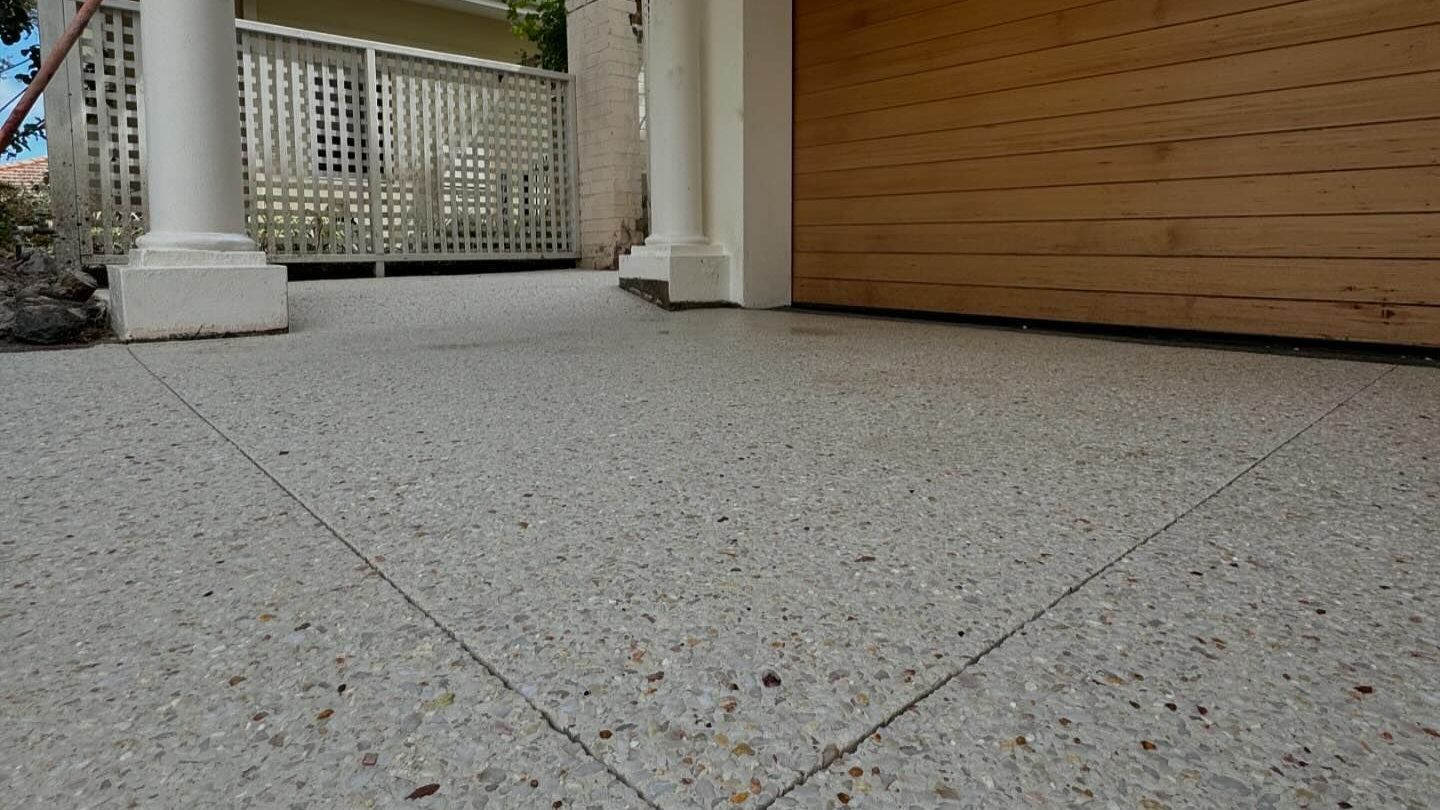 A concrete driveway with a wooden garage door in the background.