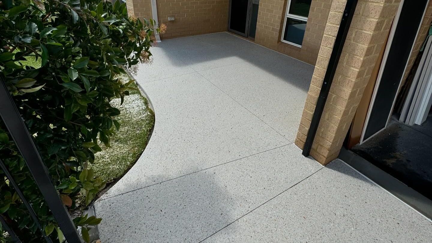Concrete pathway complimented by lush green landscape curving around Perth home. 