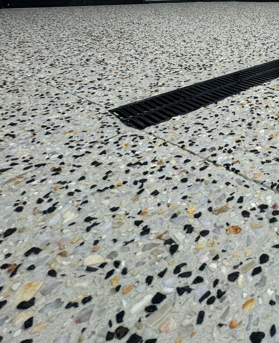 Up close of light coloured exposed aggregate with drainage.