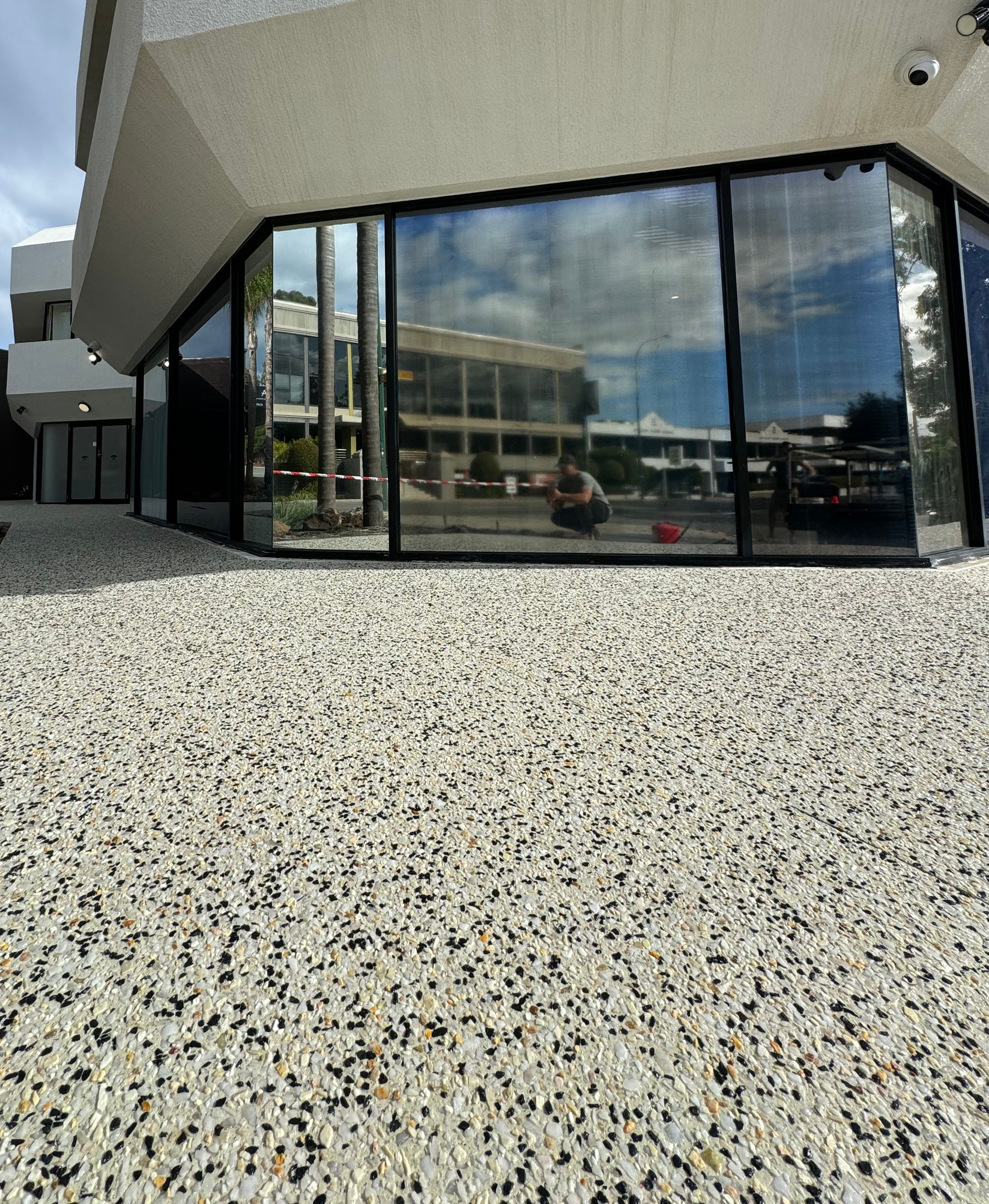 Up close of exposed aggregate laid around shop front with black framed windows