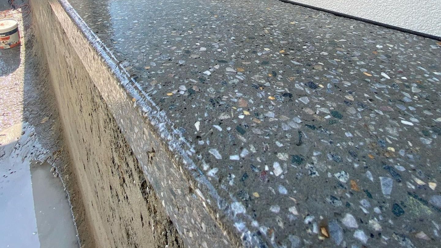 A close up of a honed concrete pool edge