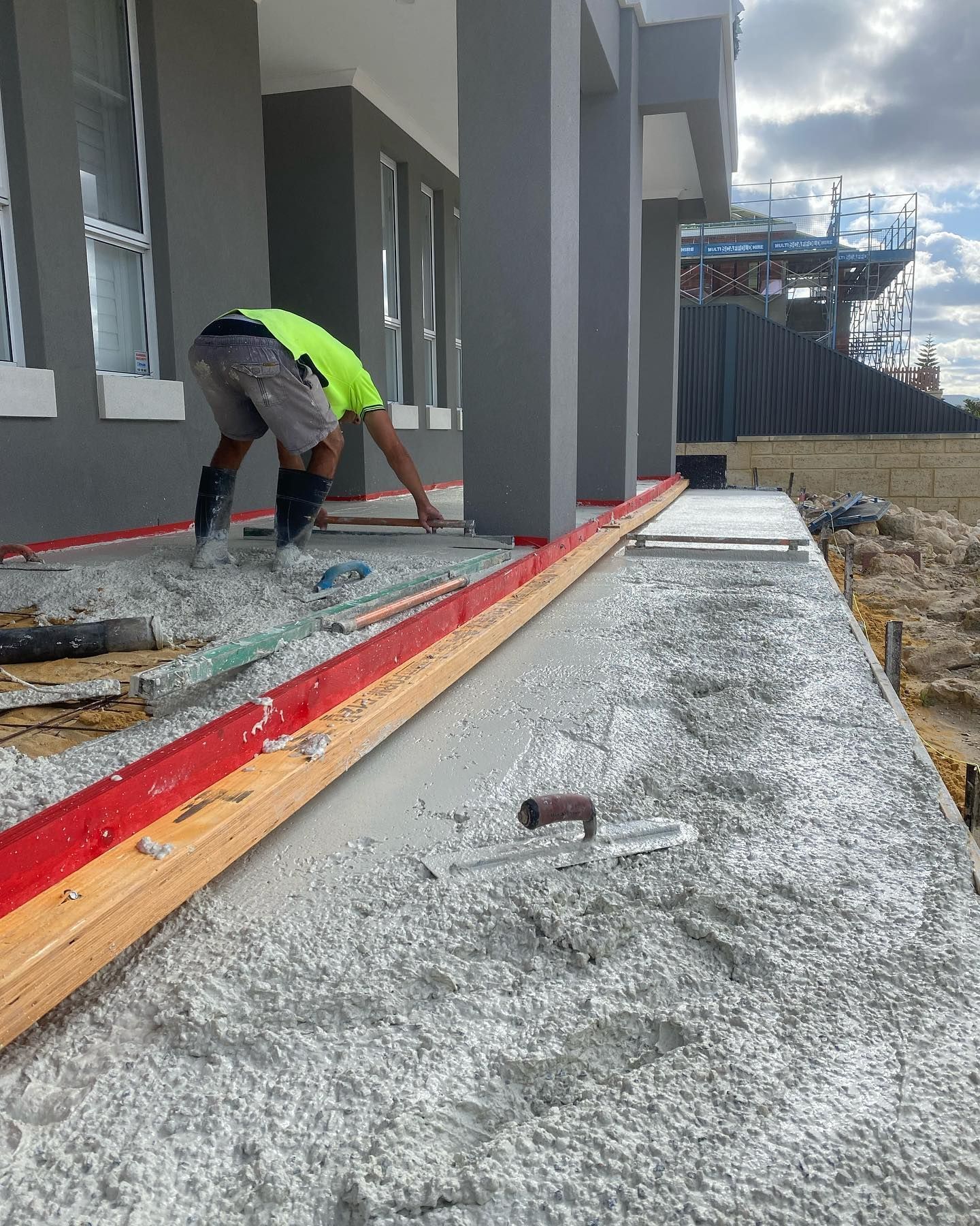 Handmade Concreting team screeding concrete for a pathway in front of the house