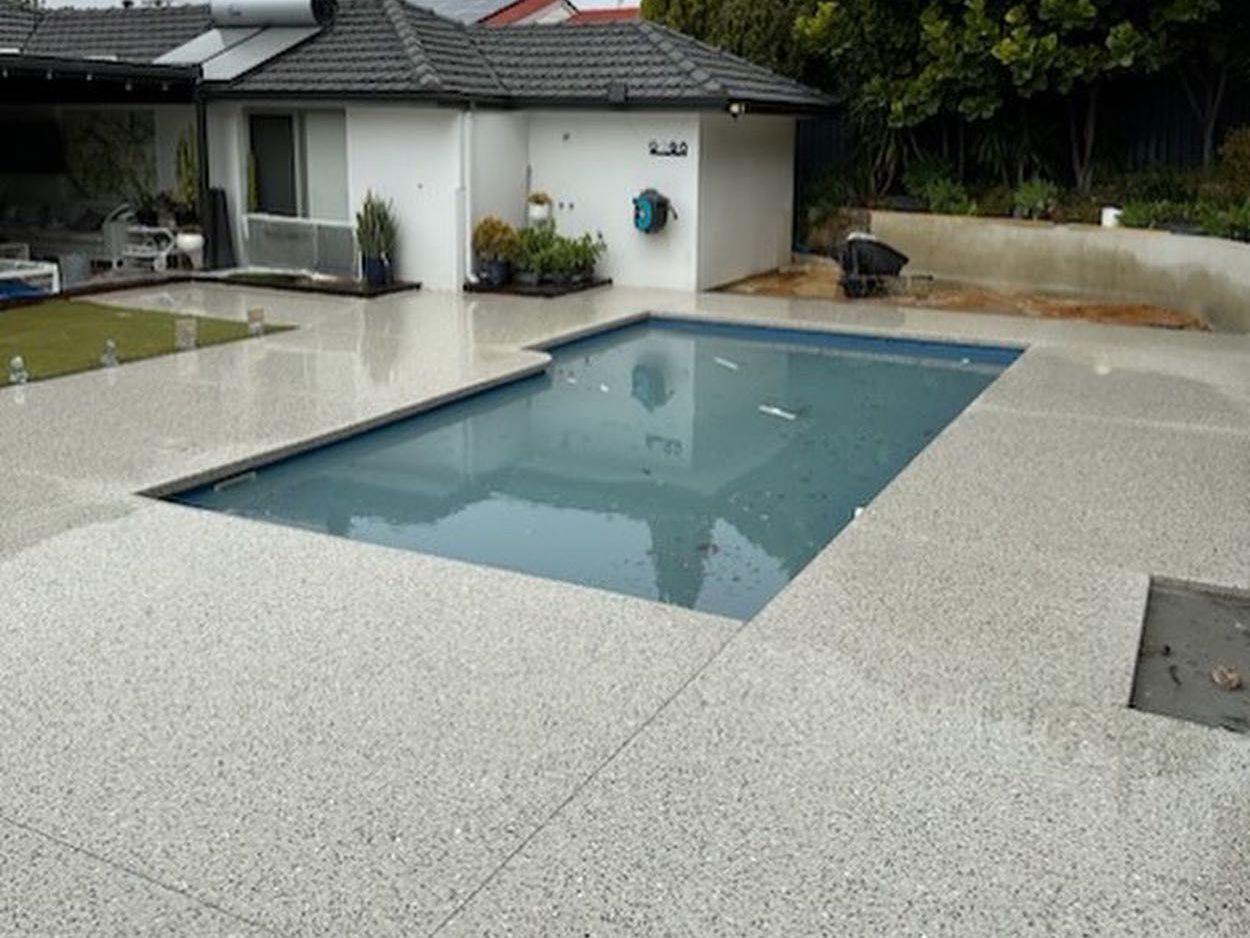 honed concrete pool surrounds in Perth backyard with house in the background.