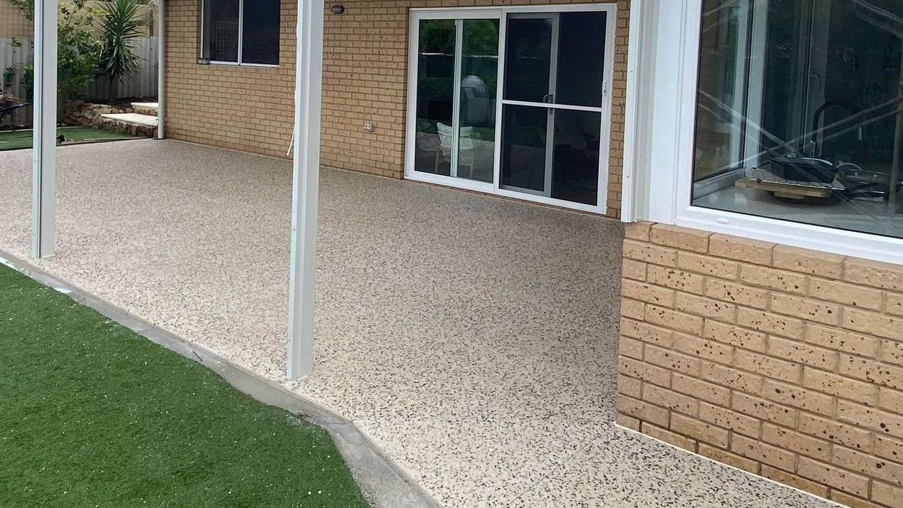 Exposed aggregate concrete patio for Perth home with green grass. 