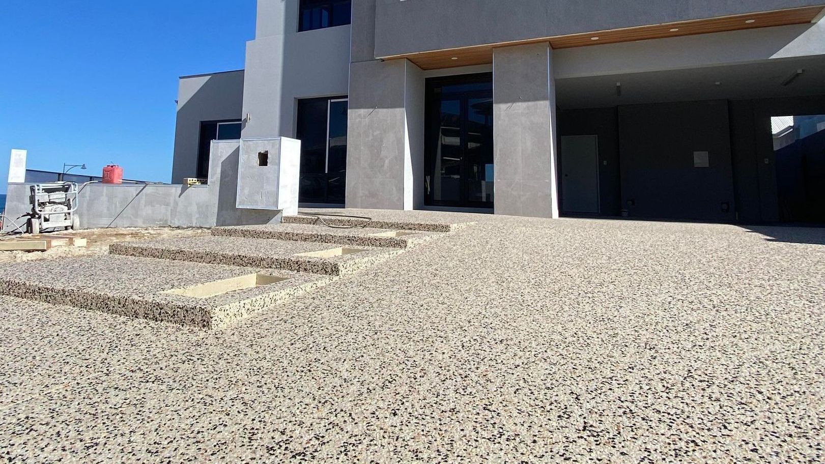 A large house with a exposed aggregate driveway in front of it.