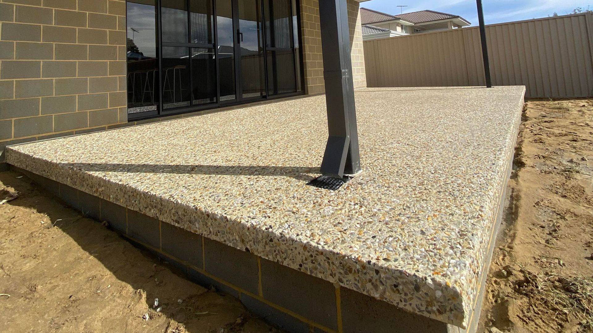 An exposed aggregate concrete deck has been built at the back of a house