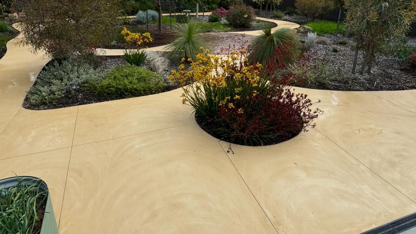 A liquid limestone walkway surrounded by flowers and trees in a garden.