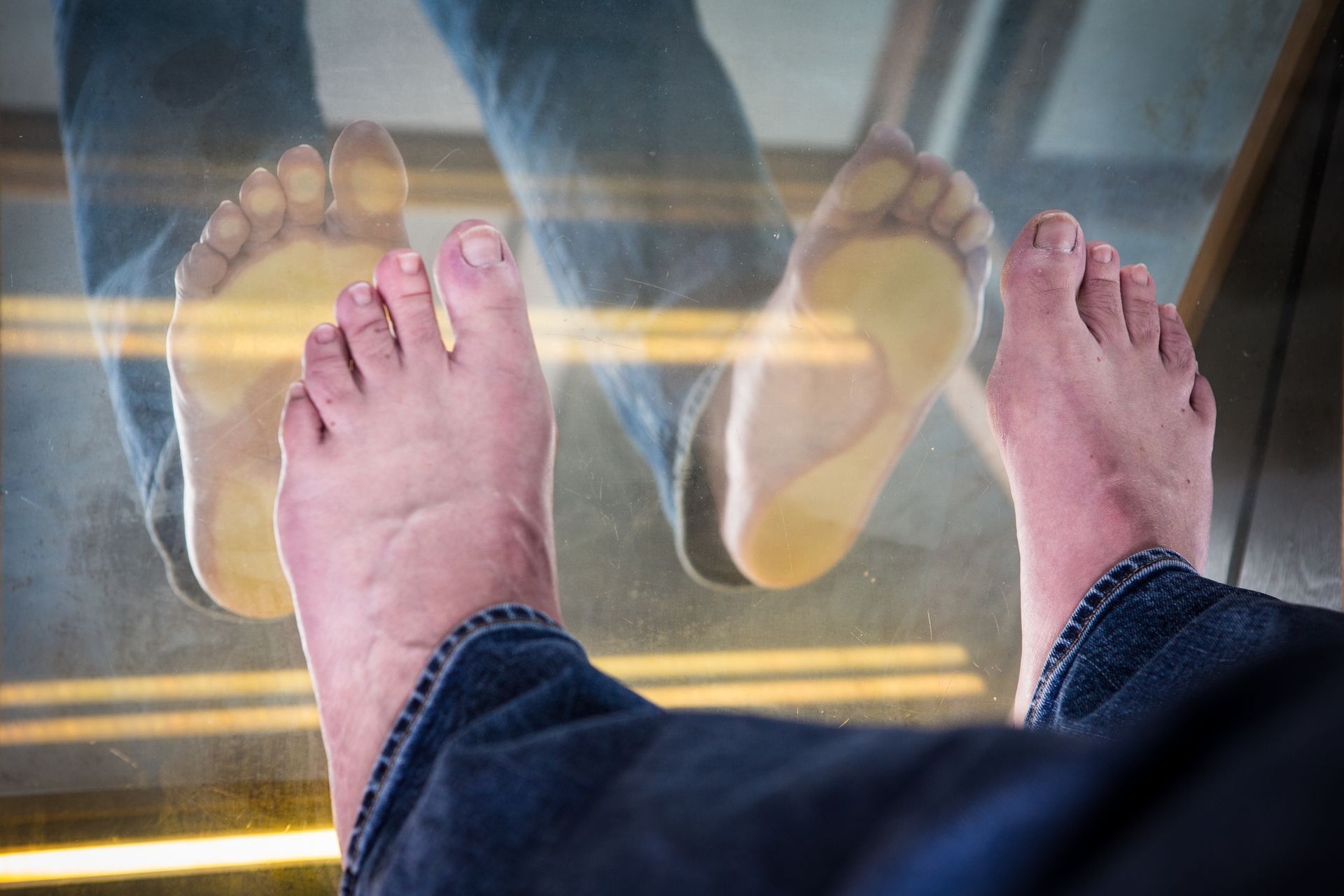 Een close-up van de voeten van een persoon op een glazen vloer.