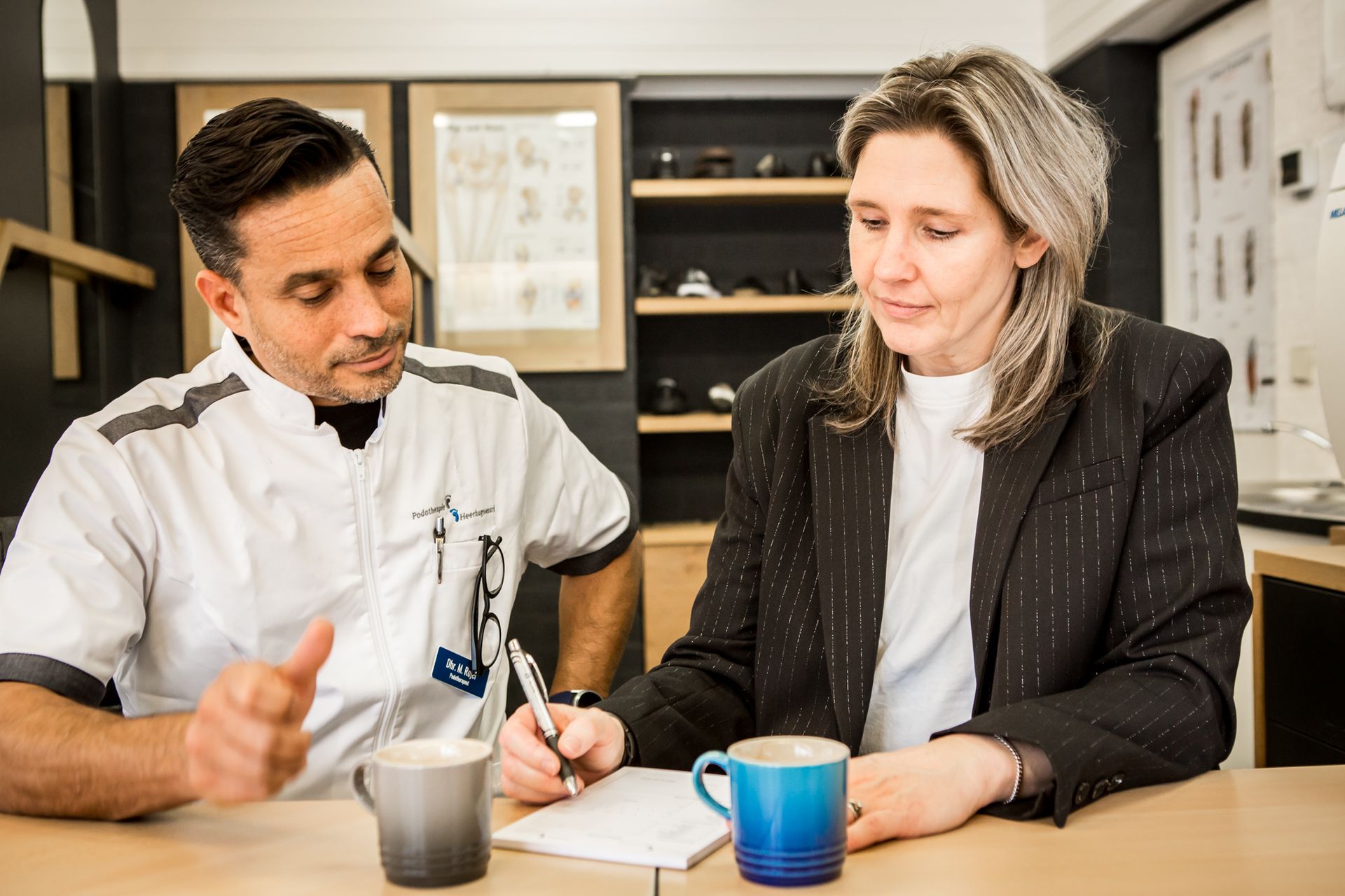 Een man en een vrouw zitten aan een tafel en kijken naar een paar sokken.