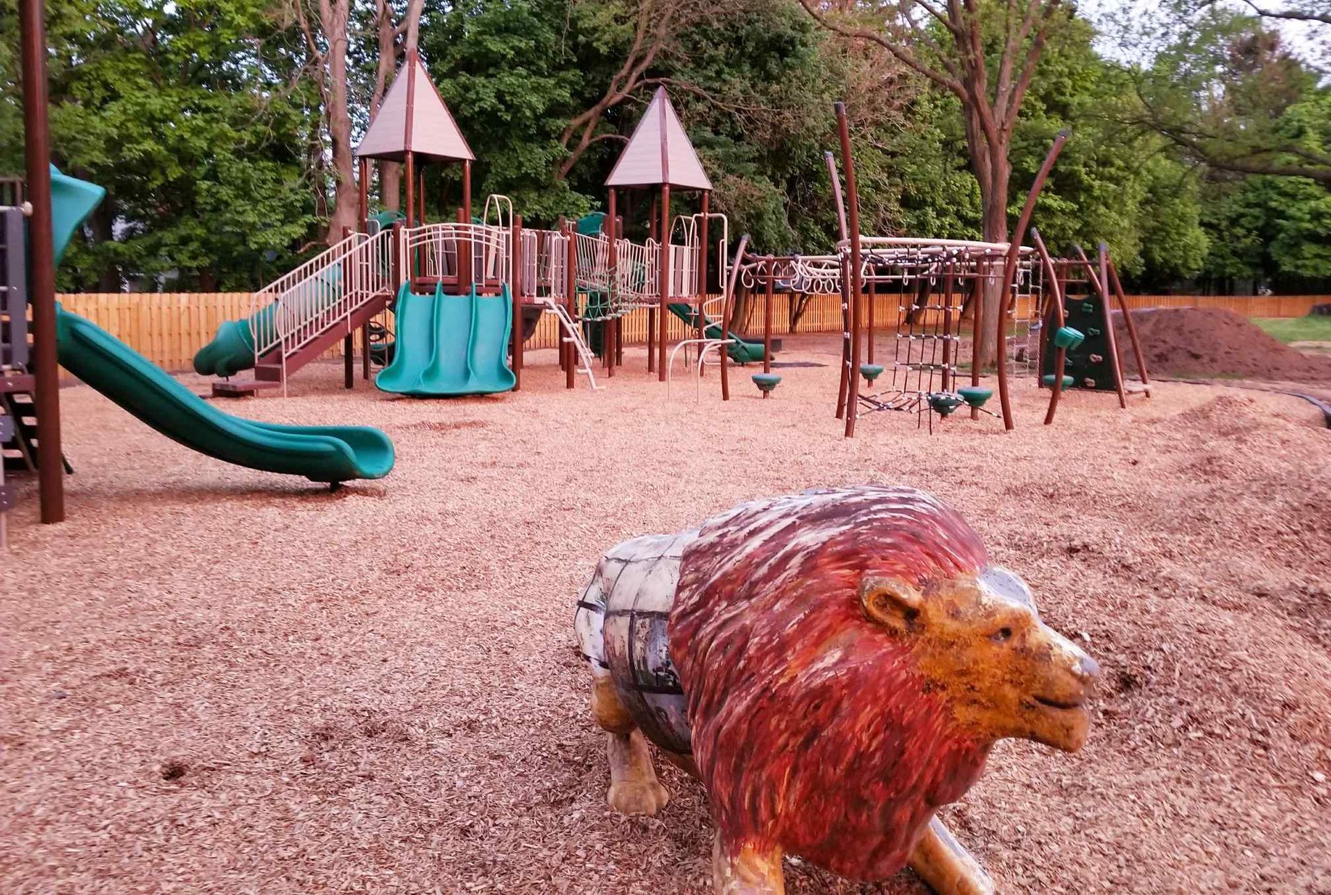 a statue of a lion is in the middle of a playground .