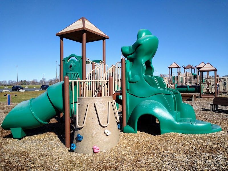 a green playground with a slide and a climbing wall