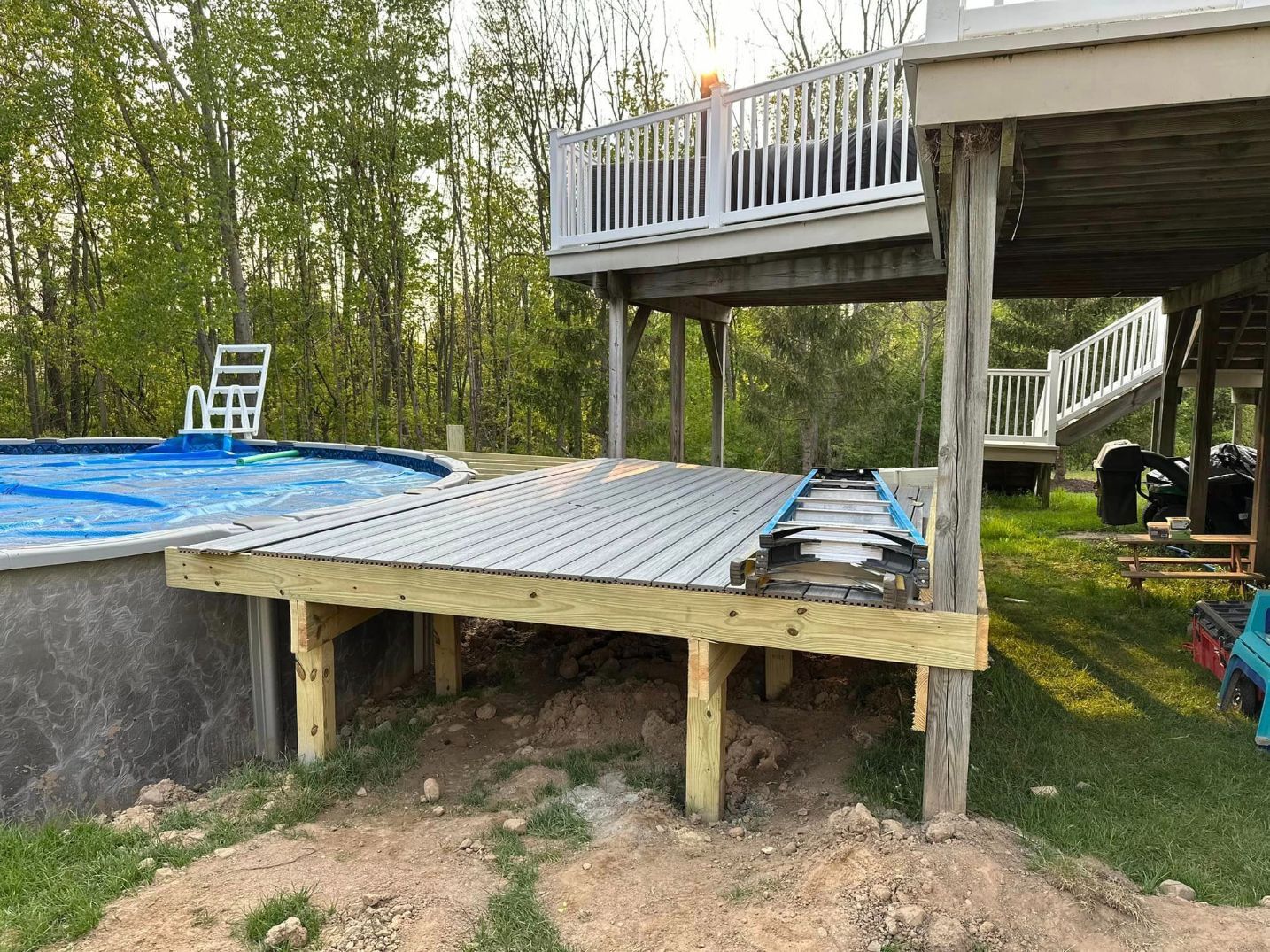 a ladder sits on a wooden deck next to a pool