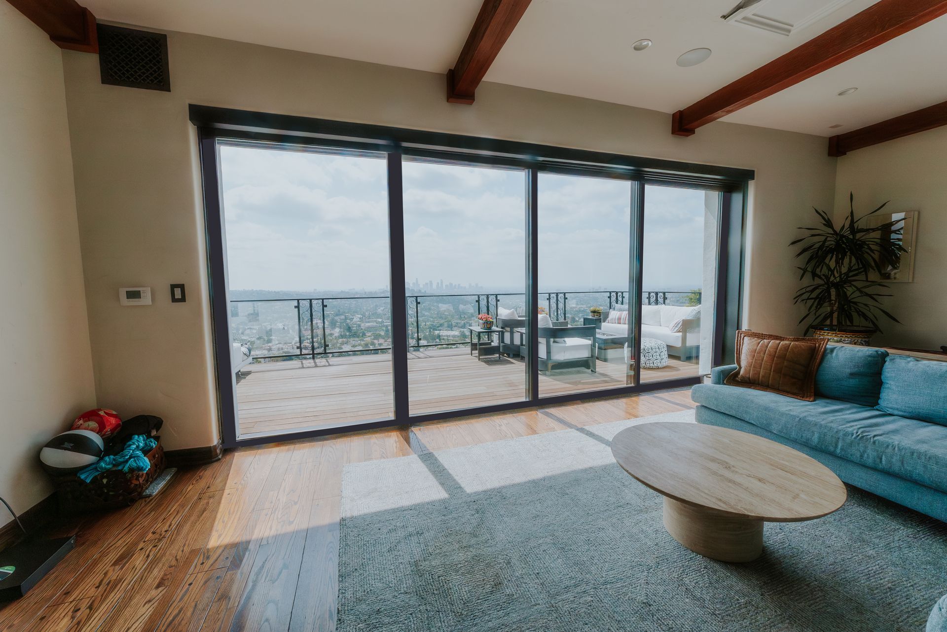 Living room with large glass doors opening to a deck overlooking a cityscape.