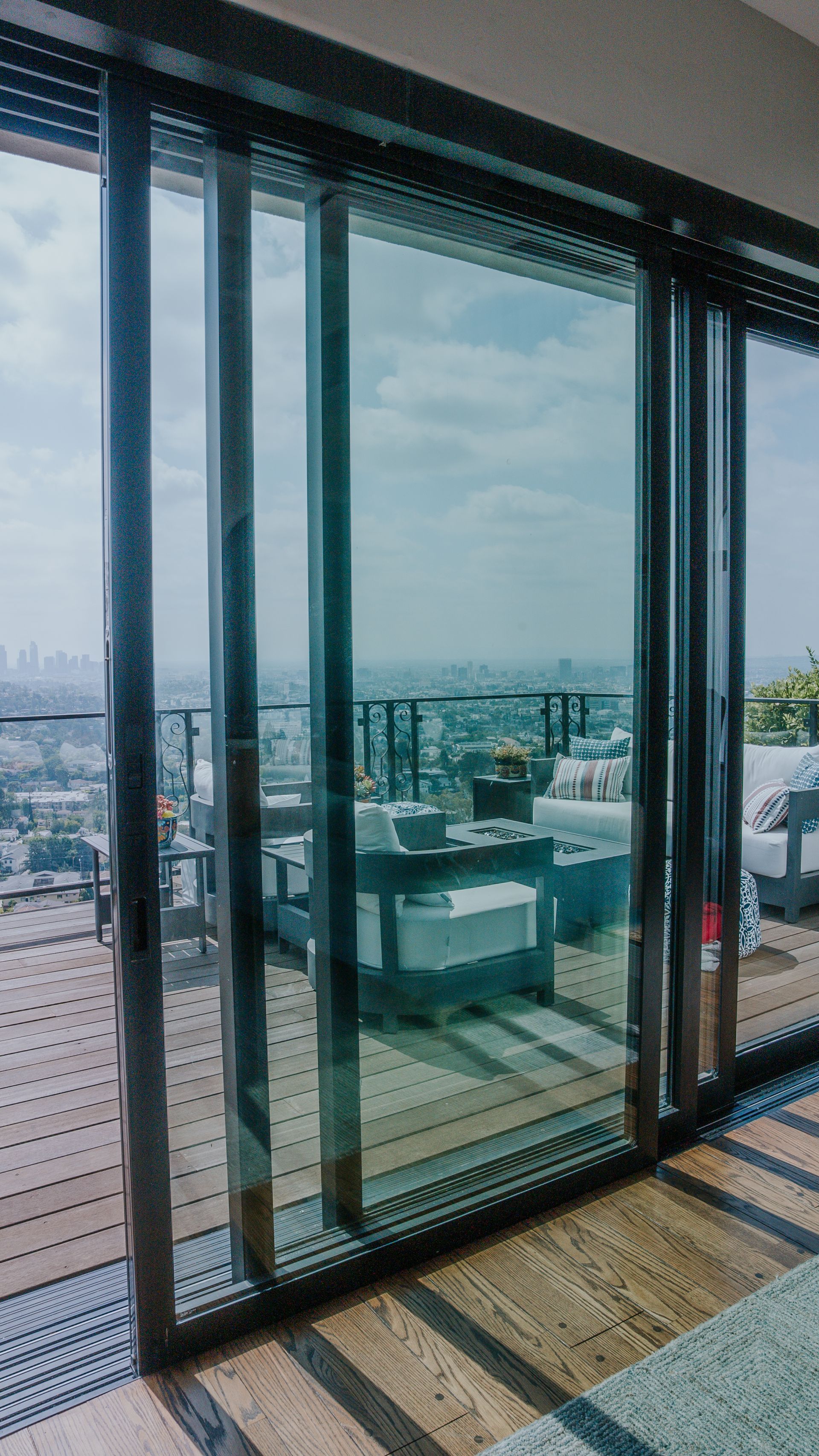 Sliding glass doors with dark frames open to a rooftop patio with city views.