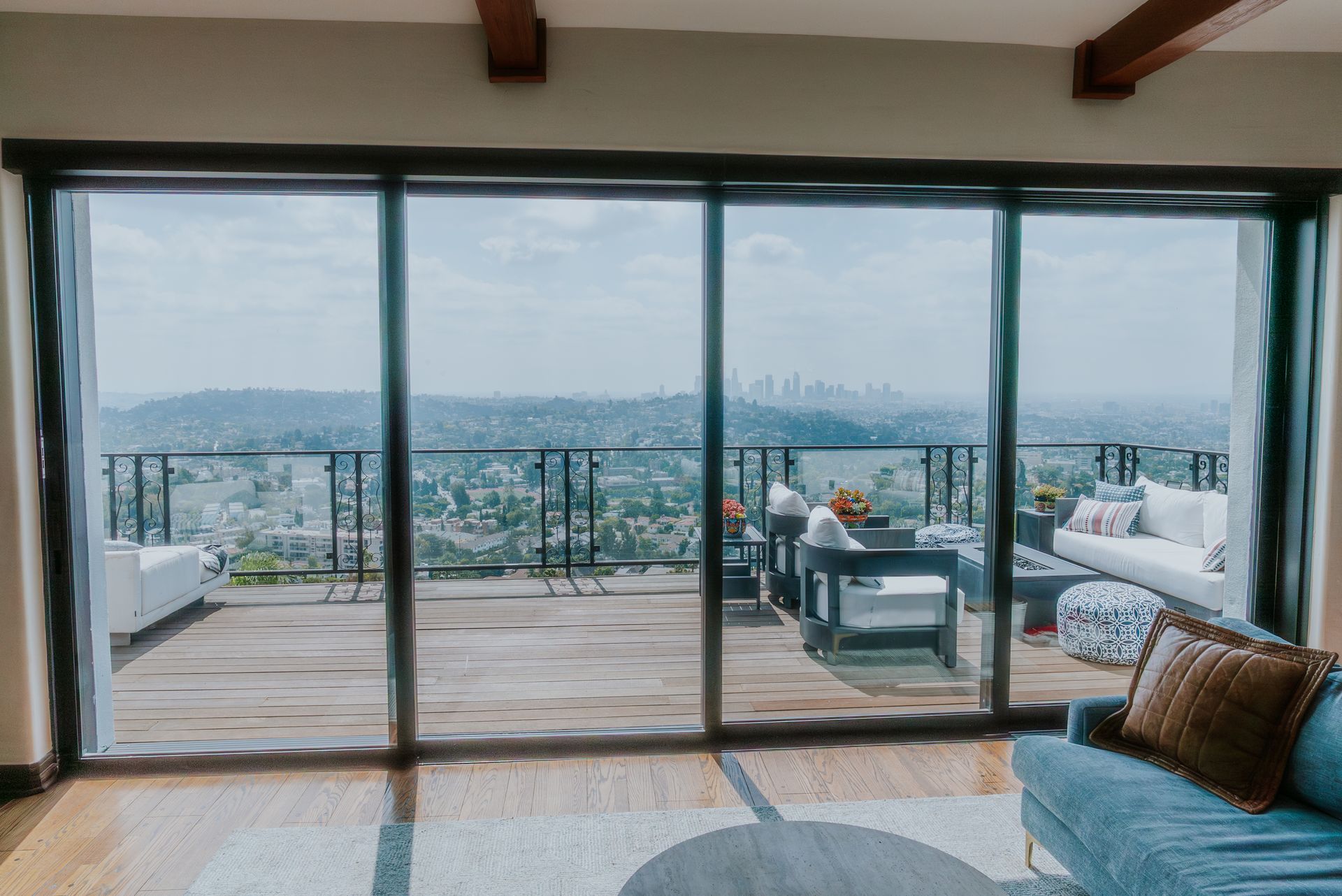 Living room with large windows overlooking a cityscape and furnished patio.