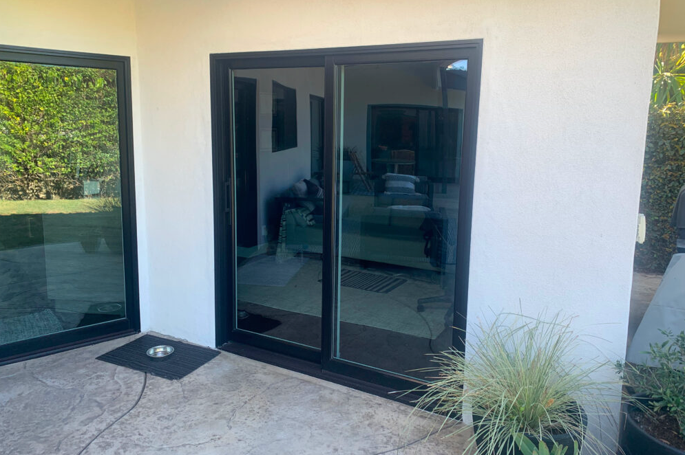 Black-framed sliding glass doors on a white wall, leading to a living room.
