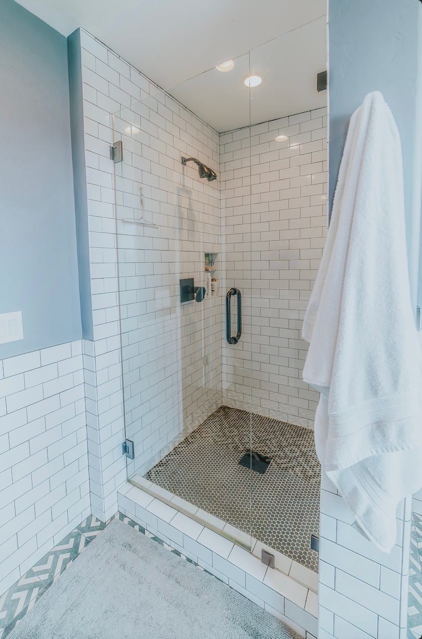 Glass shower with marble walls, showerheads, and a built-in bench.