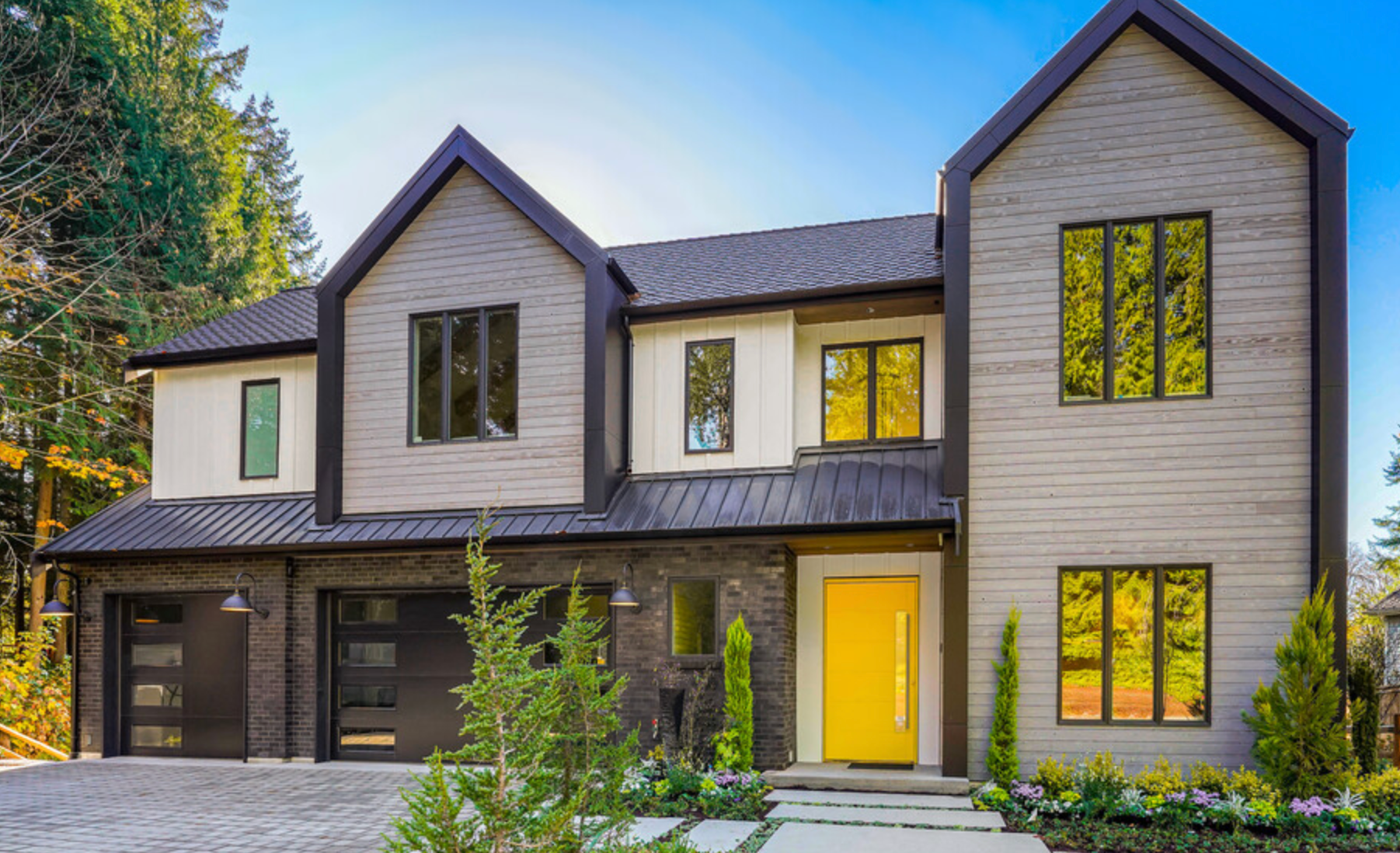 Black framed windows with arched windows. View of trees and a house through the window.