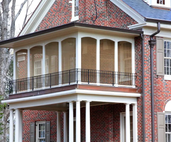Brick house with screened-in porch and black railing; white columns and trim.
