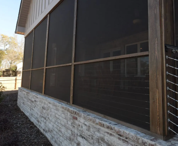 Screened-in porch with dark mesh and wooden framing, set on a brick foundation.