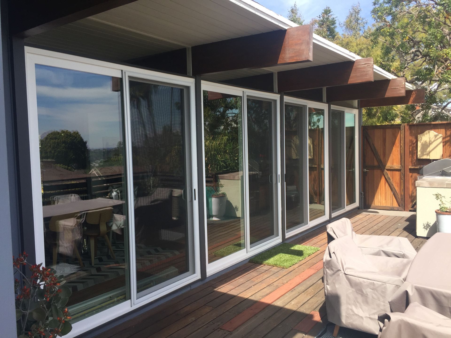Sliding glass doors on a deck, reflecting the interior and surrounding trees.