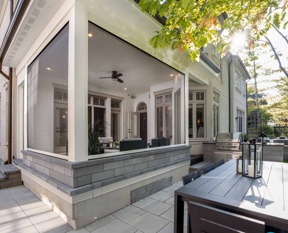 Modern covered porch with white columns, gray siding, and outdoor seating beside a home
