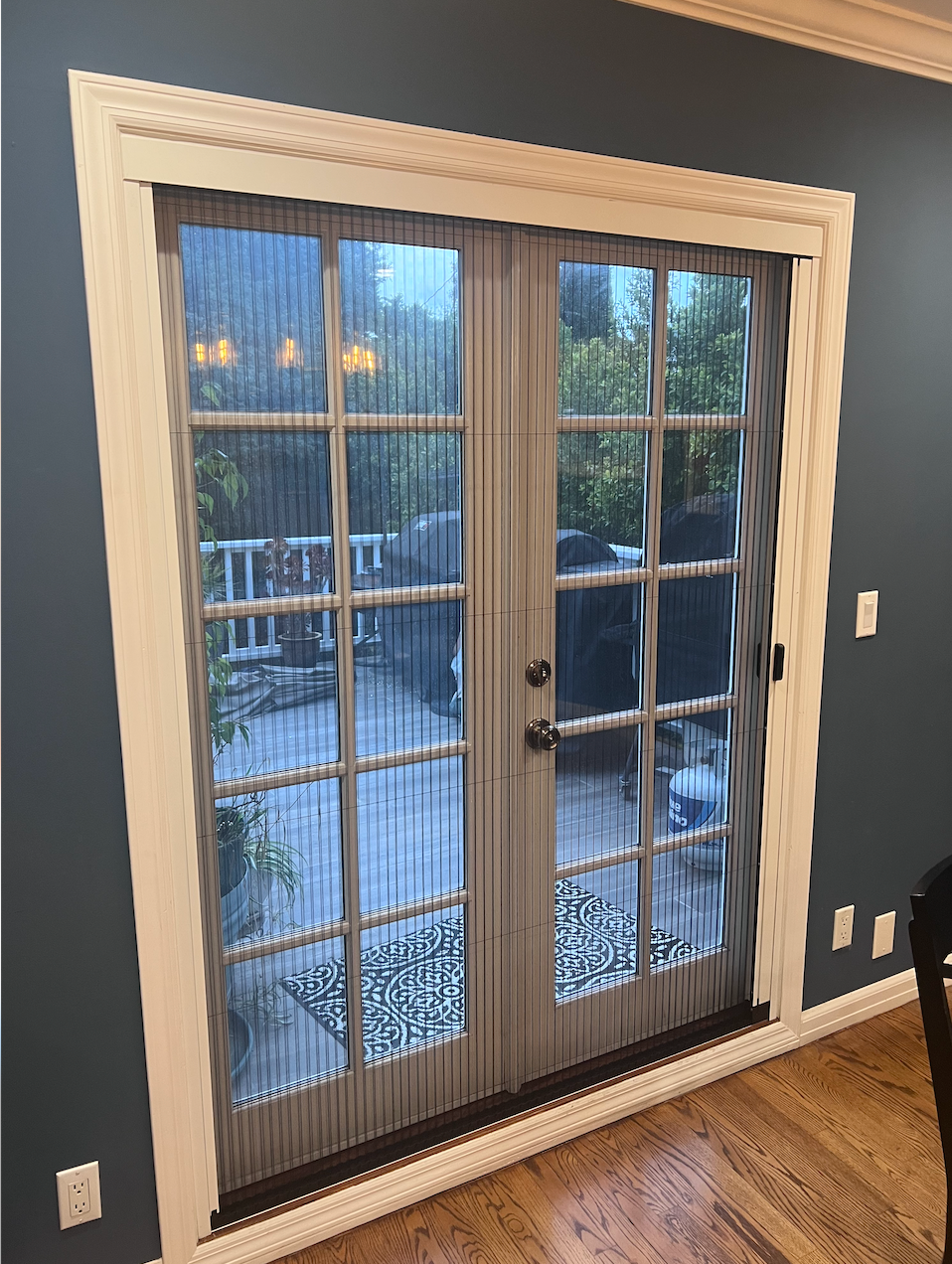 French doors with vertical blinds opening to a snowy outdoor deck