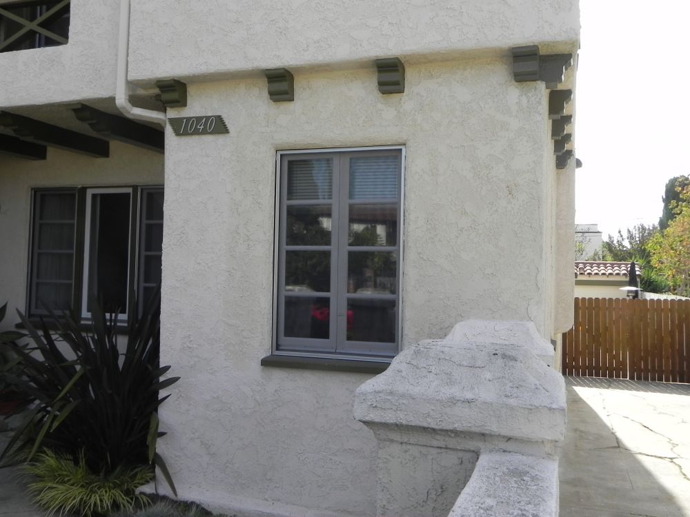 Open arched windows with white frames, overlooking greenery and a balcony.