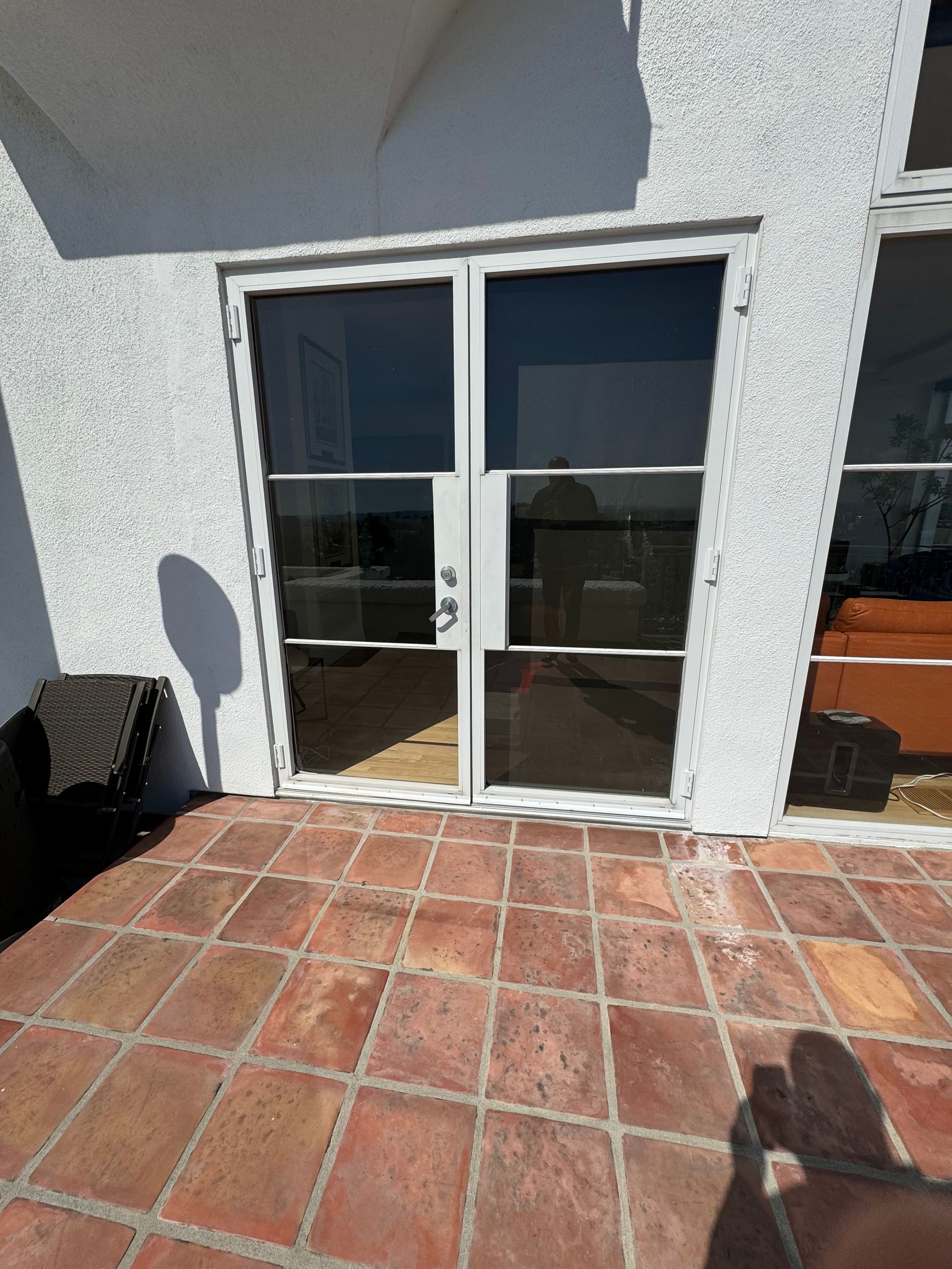 Double glass doors in white frame, opening onto a brick patio. Shadow of a person on the bricks.